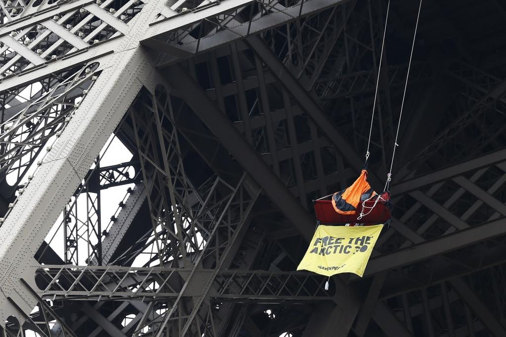 FOTO: Greenpeace aktīvists iekaras Eifeļa tornī, protestējot pret savu biedru turēšanu cietumā Krievijā